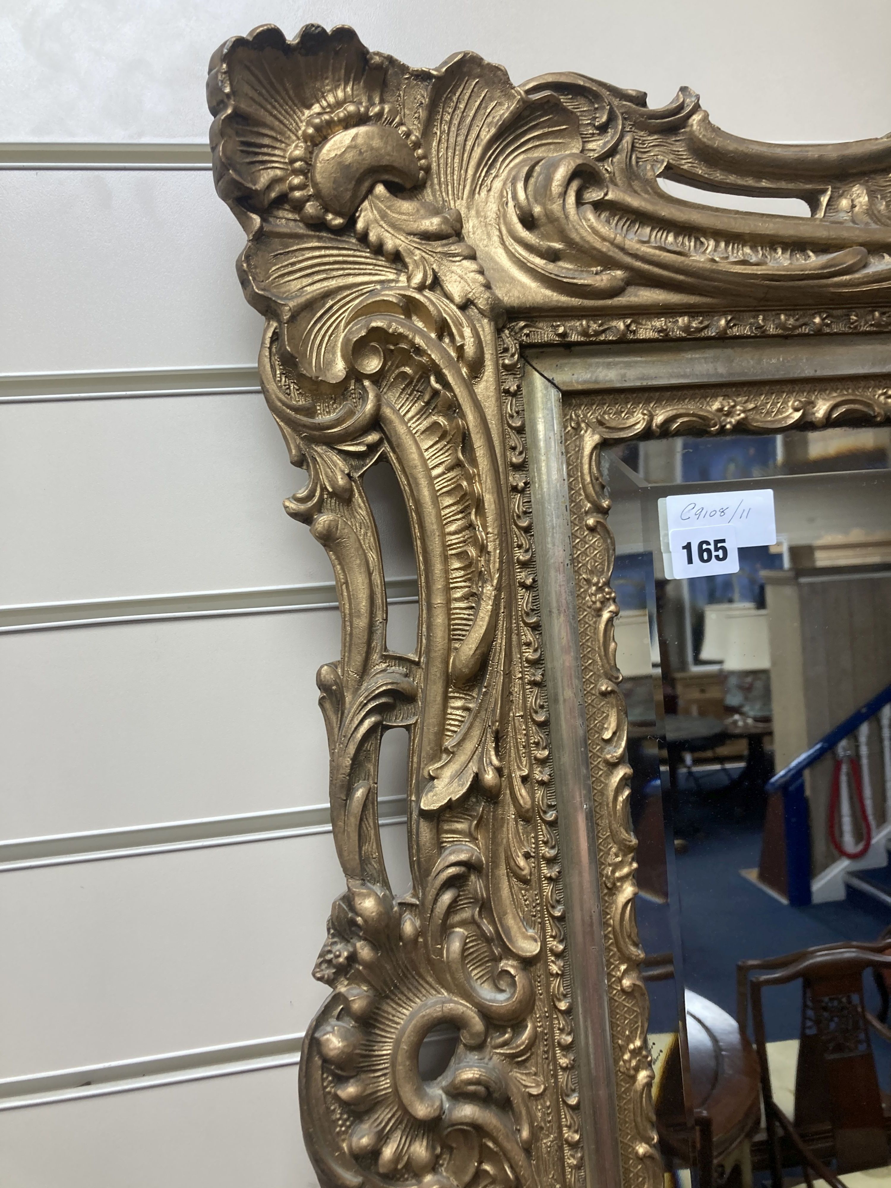 A rectangular carved and pierced framed gilt wall mirror in the rococo style, stepped and moulded border enclosing a bevelled plate, wi